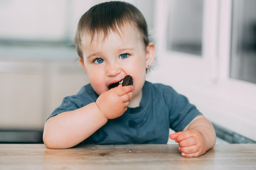 Little girl in the kitchen eating marshmallows in chocolate or chocolate chip cookies