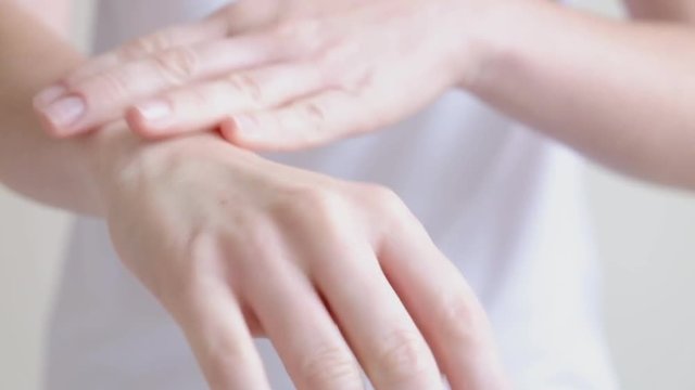 Hands of a young woman applying hand cream, hands massage