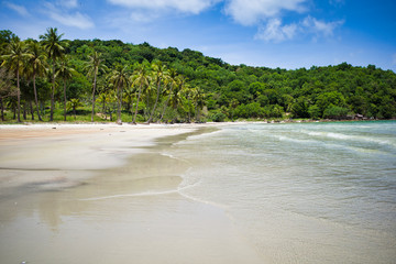 Phu Quoc island, Vietnam - March 31, 2019: White sand beach, calm sea. Rocky hills, growing palms and tropical trees. Beautiful coast of the South China Sea