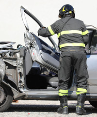 fireman removes the door of a destroyed car after a car accident