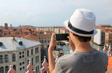 young boy with white hat takes picutres with smartphone