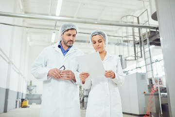 Two technologists in lab coats and masks at the factory.