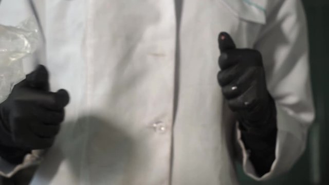 Scientist puts on protective black gloves in the laboratory before experiment