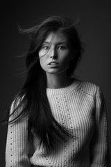 .black and white beautiful model girl with long hair in the Studio on a gray background in a jacket of large knit