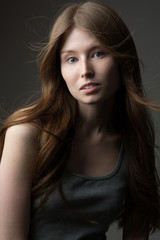 Fototapeta premium beautiful redhead model girl with long hair in the Studio on a gray background in a t-shirt