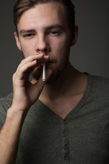 Portrait of a young Caucasian Smoking man with a short beard and mustache on a dark background