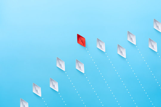 Business competition and leadership concepts with red and white paper ships on blue background. copy space