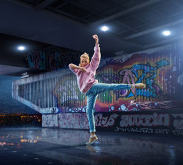 Female Hip Hop Dancer. Beautiful girl dancing at night on the background of graffiti wall
