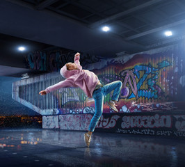 Female Hip Hop Dancer. Beautiful girl dancing at night on the background of graffiti wall