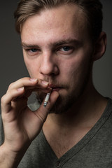 Portrait of a young bearded Caucasian Smoking man with bad skin, circles under his eyes, concept: Smoking is dangerous for health
