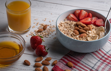 Healthy breakfast. Oatmeal, muesli with berry, honey, nuts on bowl with a cup of juice on white background.