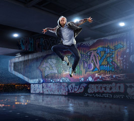 Male Hip Hop Dancer. Beautiful man dancing at night on the background of graffiti wall