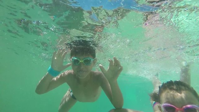Happy boy and girl swim in the pool under water