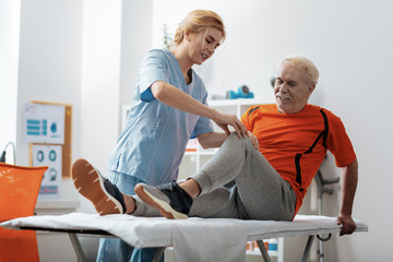 Obraz premium Nice blonde woman touching her patients knee