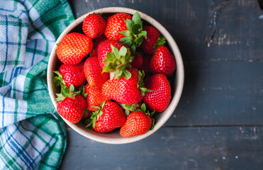 Close-up of fresh strawberries in a bowl on wooden background, top view