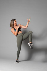Obraz premium Beautiful caucasian fitness Models does pointing gestures for product or icon placements on a gray background. 