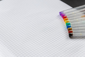 Bunte Farbstifte mit Glitzer liegen bereit auf einem karierten Blatt Papier für Malen, Zeichnen...