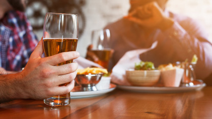 Male Hand Holding Beer Glass, Resting In Bar With Friends