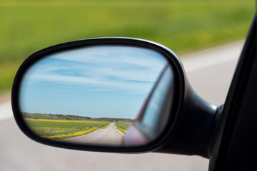 View of the highway in the side mirror of the car. Distance traveled.
