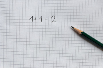 Einfache Rechenaufgabe für Grundschüler zum Schulanfang auf einem karierten Blatt Papier mit...