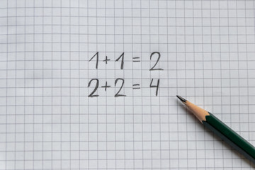 Einfache Rechenaufgabe f&uuml;r Grundsch&uuml;ler zum Schulanfang auf einem karierten Blatt Papier mit Bleistift
