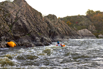 Man in blue kayak on whitewater on fast mountain river among the rapids at dusk. Whitewater kayaking, extreme water sport. Kayak freestyle