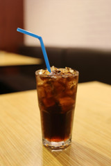 Glass of cold cola on food table.