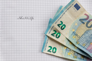 Nachhihlfe ist wertvoll - dargestellt mit 20-EURO-Scheinen und dem Wort Nachhilfe auf kariertem Blatt Papier