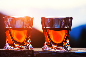 shot of whiskey at sunset dramatic sky on mountain landscape background