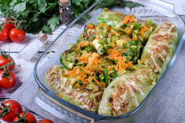 Raw cabbage rolls with fried vegetables in a glass dish ready to be roasted