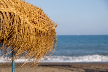 straw umbrellas on the beach with sea in the background
