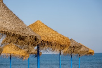 Fototapeta na wymiar straw umbrellas on the beach with sea in the background