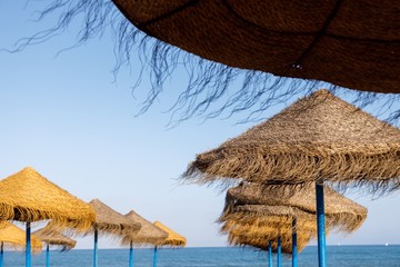 straw umbrellas on the beach with sea in the background