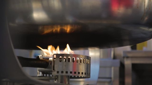 Fiamma di un fornello a gas con grande padella wok in alluminio di un ristorante asiatico Giapponese per la cottura dei cibi. Video al rallentatore.