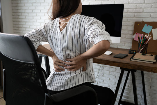 Business woman suffering from back pain in office home