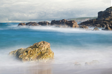 costa en la playa con mar suave, espuma blanca y cielo con nubes de tormenta