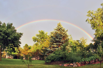 Summer landscape with private house backyard.Scenic view with rainbow over the lawn and trees on a back yard in the private houses neighborhood. Summer time background. Midwest USA, Wisconsin, Madison