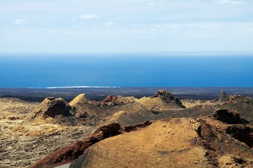 Fototapeta na wymiar Panoramic view over waste lava field on endless blurred horizon of Atlantic ocean in Timanfaya NP, Lanzarote, Canary Islands