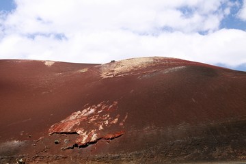 Panoramic view on surreal abstract red burning volcanic mountain (Montañas del Fuego) against blue...