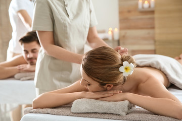 Obraz na płótnie Canvas Romantic young couple enjoying herbal bag massage in spa salon