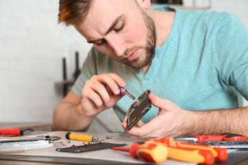 Technician repairing mobile phone at table in workshop, closeup