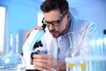 Male scientist using modern microscope in chemistry laboratory