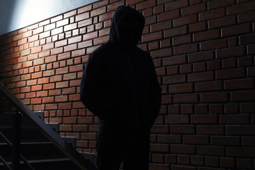 Silhouette of mysterious man in hoodie indoors. Dangerous criminal
