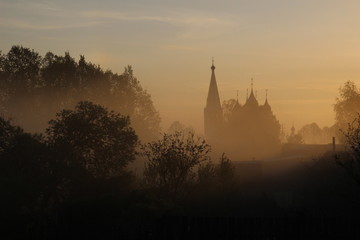 Obraz premium Trees and church silhouettes in misty summer morning