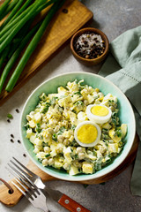 Summer vitamin salad with egg and green peas on a bright stone or slate table. Rustic style.
