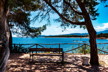 Fototapeta na wymiar Santa Maria Navarrese, Sardinia, Italy - A beautiful seat in the shade, on a bench, at the old tower, overlooking the coastal landscape, on a sunny day in May.