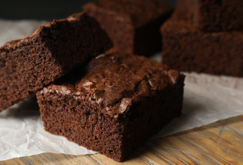 Fresh brownies on wooden board, closeup. Delicious chocolate pie