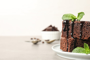 Fresh brownies with sauce and mint on table, space for text. Delicious chocolate pie