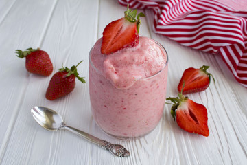 Smoothies with strawberries in the glass on the white wooden background