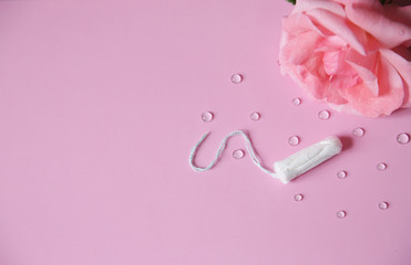 Clean white cotton tampon on pink background with drops. Isolated. Copy space. Menstruation. Feminine Hygiene in periods, beauty treatment. Flat lay.